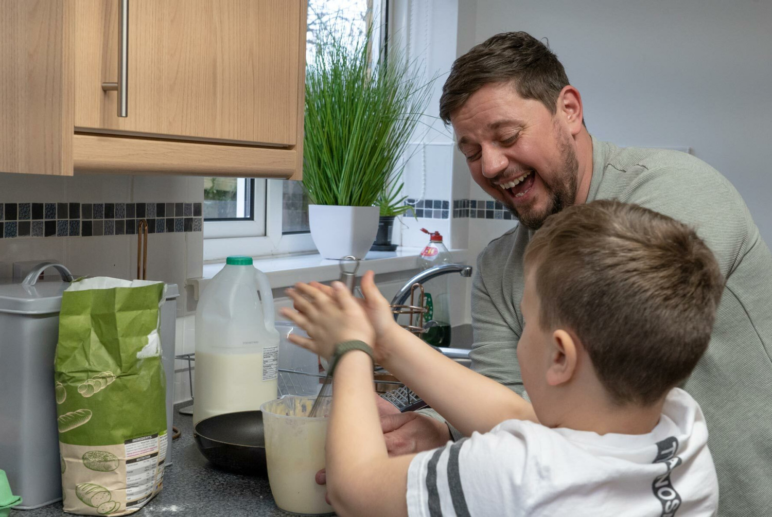 A residential child care worker helping a child make pancakes