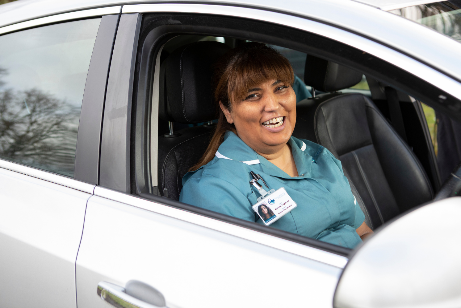 Karima, a home care worker sat in her car smiling