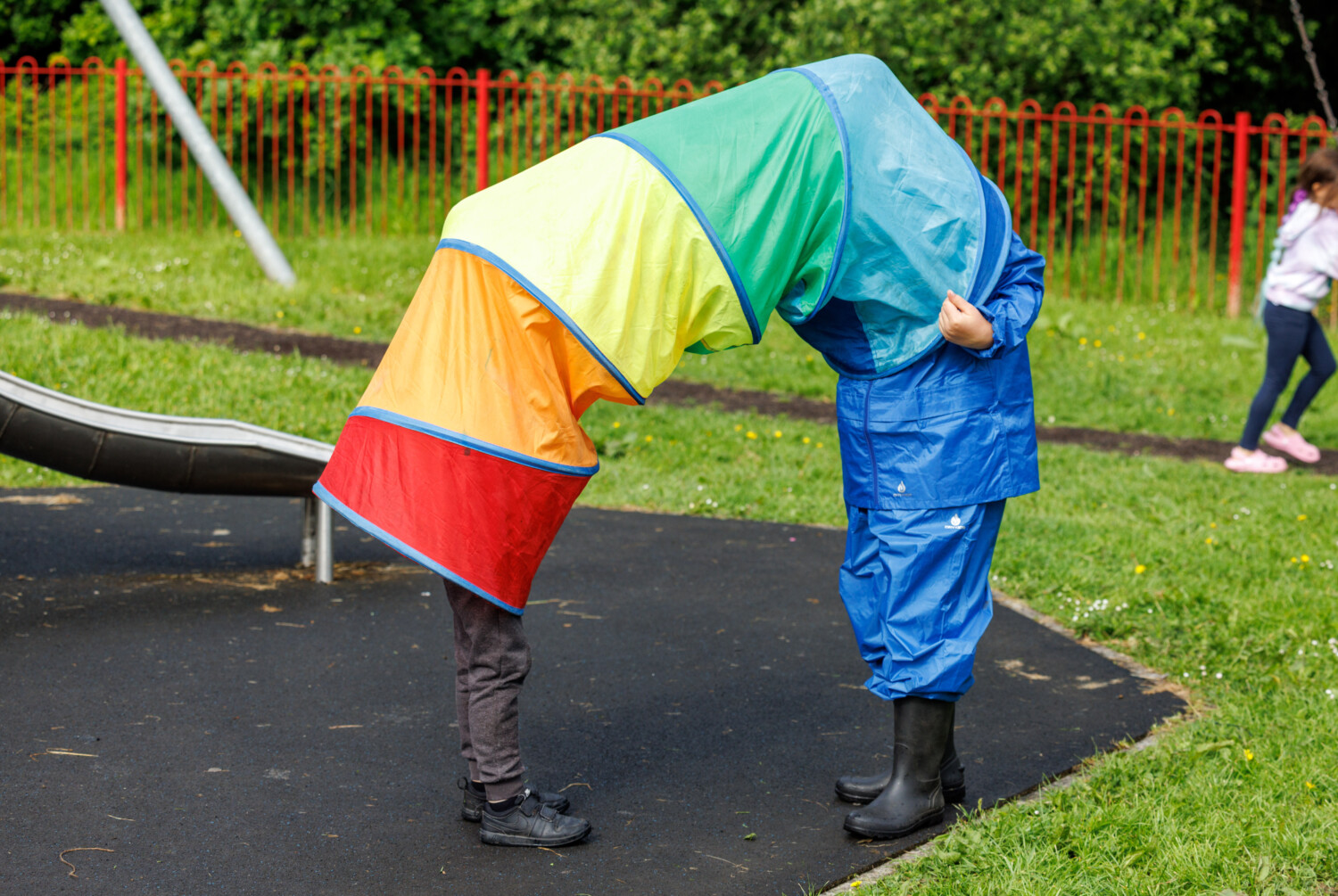 Two children playing in a colourful play tunnel with only their feet visible