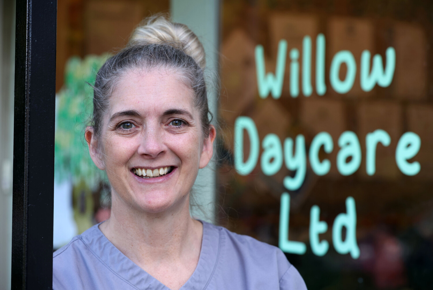 Close up of a carer in front of a Willow Daycare Ltd sign
