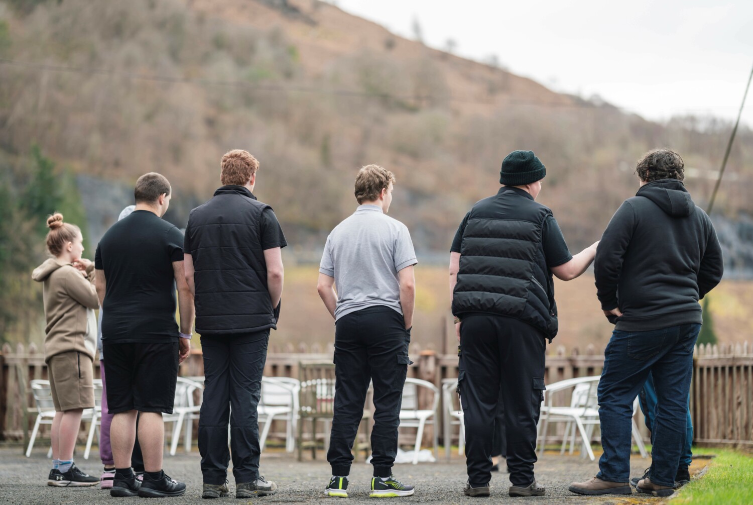 6 young people with their backs to the camera looking out at a view in country