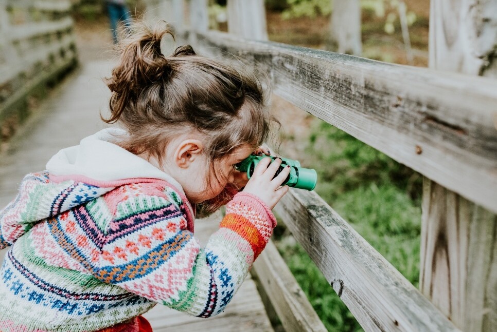 Small child looking through a bridge with binoculars
