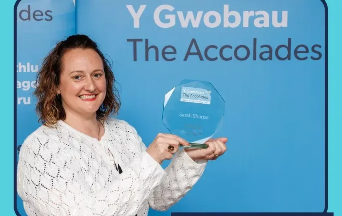Sarah holding their award.